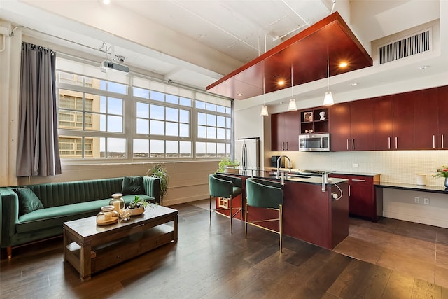 kitchen featuring sink, a breakfast bar area, appliances with stainless steel finishes, an island with sink, and backsplash