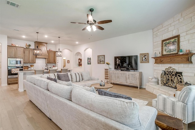 living room with ceiling fan, light hardwood / wood-style floors, and a fireplace