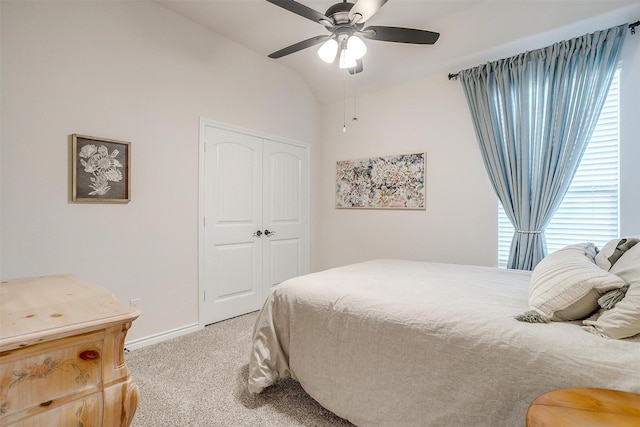 carpeted bedroom with ceiling fan, a closet, and vaulted ceiling