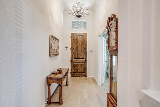 interior space featuring plenty of natural light, light hardwood / wood-style flooring, a high ceiling, and an inviting chandelier