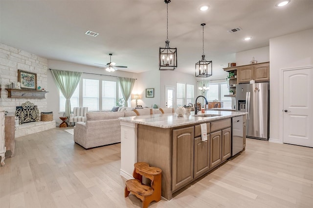 kitchen featuring a kitchen island with sink, sink, stainless steel appliances, and light wood-type flooring