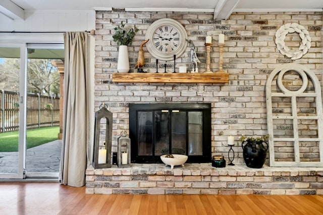 room details with hardwood / wood-style flooring, beamed ceiling, and a brick fireplace