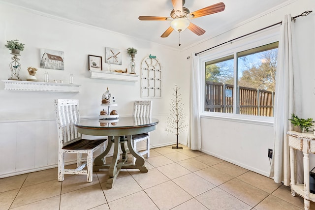 tiled dining area with ceiling fan and ornamental molding