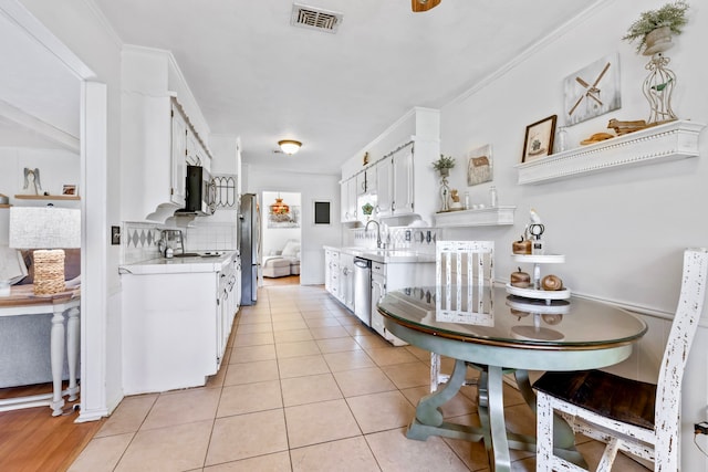 kitchen with white cabinetry, light tile patterned floors, ornamental molding, and appliances with stainless steel finishes