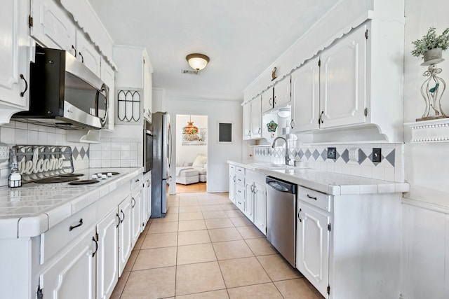 kitchen with tile counters, sink, tasteful backsplash, white cabinets, and appliances with stainless steel finishes