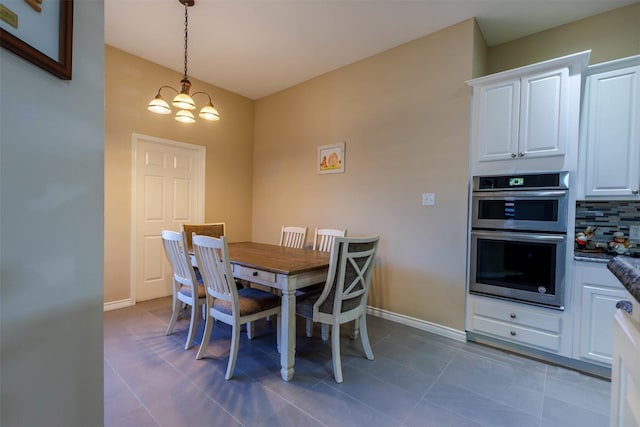 dining room with dark tile patterned floors and a notable chandelier