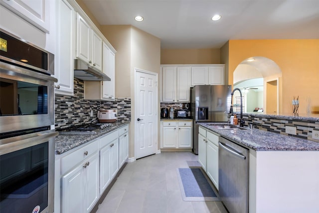 kitchen with backsplash, dark stone countertops, sink, white cabinetry, and stainless steel appliances