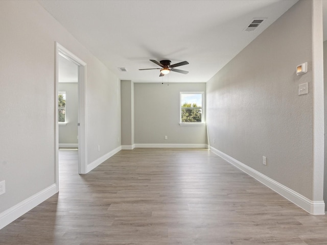 unfurnished room featuring ceiling fan, light hardwood / wood-style flooring, and a healthy amount of sunlight