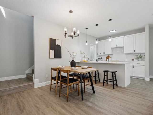 dining space featuring a chandelier, sink, and light hardwood / wood-style flooring