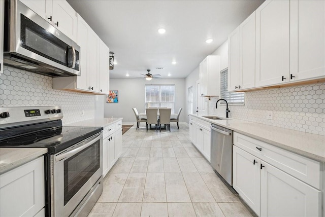 kitchen featuring white cabinets, ceiling fan, sink, and stainless steel appliances