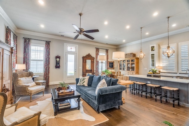 living room with crown molding, light hardwood / wood-style floors, and ceiling fan with notable chandelier