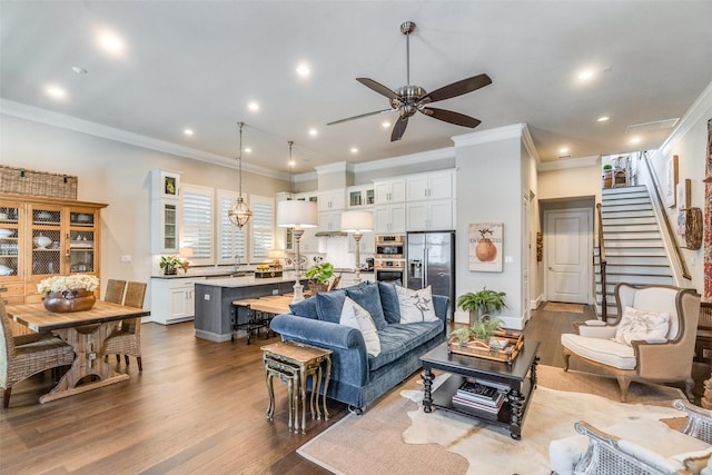 living room with wood-type flooring, ceiling fan, and ornamental molding