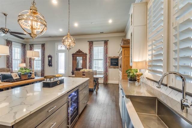 kitchen with beverage cooler, crown molding, sink, pendant lighting, and dark hardwood / wood-style floors