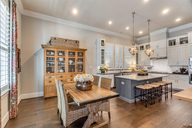 kitchen with a breakfast bar, sink, decorative light fixtures, white cabinets, and a kitchen island