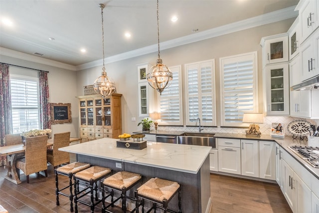 kitchen with white cabinetry, sink, dark stone countertops, pendant lighting, and a kitchen island