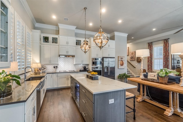 kitchen with white cabinets, stainless steel appliances, a kitchen island, and sink