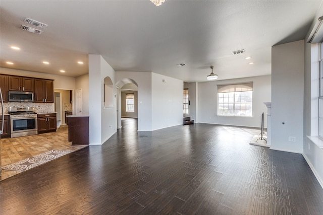 unfurnished living room featuring a wealth of natural light and dark wood-type flooring