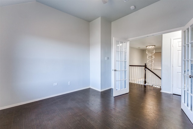 empty room featuring french doors, dark wood-type flooring, lofted ceiling, and a notable chandelier