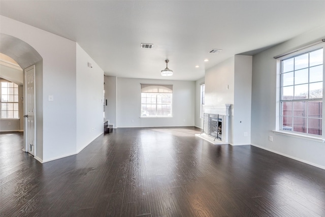 unfurnished living room with a wealth of natural light and dark hardwood / wood-style flooring