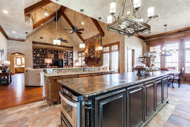 kitchen featuring sink, hanging light fixtures, dark stone counters, a healthy amount of sunlight, and a large island