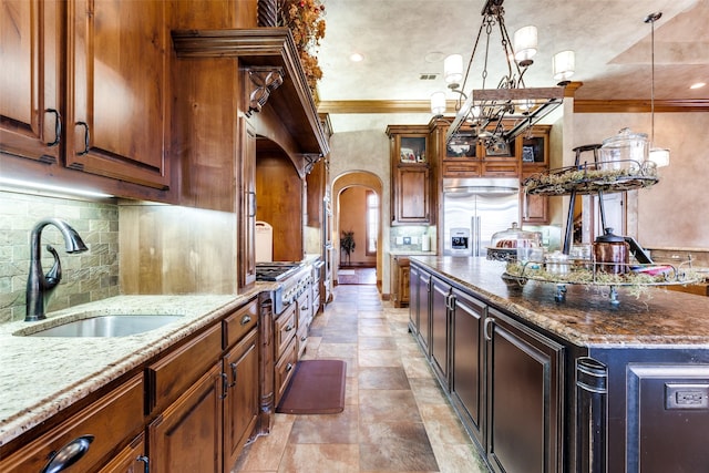 kitchen with sink, appliances with stainless steel finishes, hanging light fixtures, a center island, and light stone counters