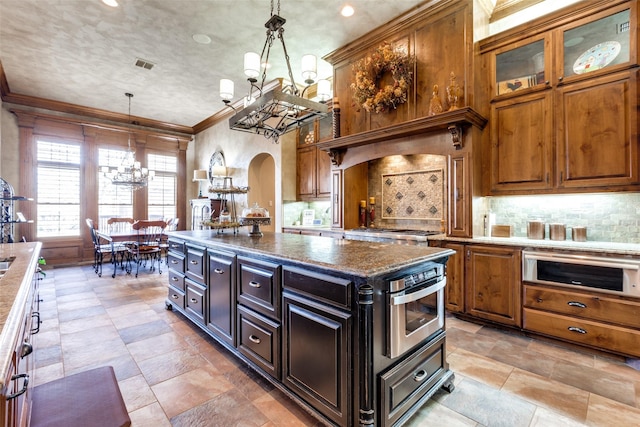 kitchen featuring a kitchen island, dark stone countertops, a chandelier, and decorative light fixtures