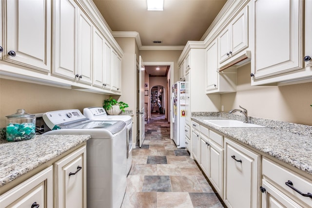 laundry room with cabinets, washing machine and clothes dryer, crown molding, and sink