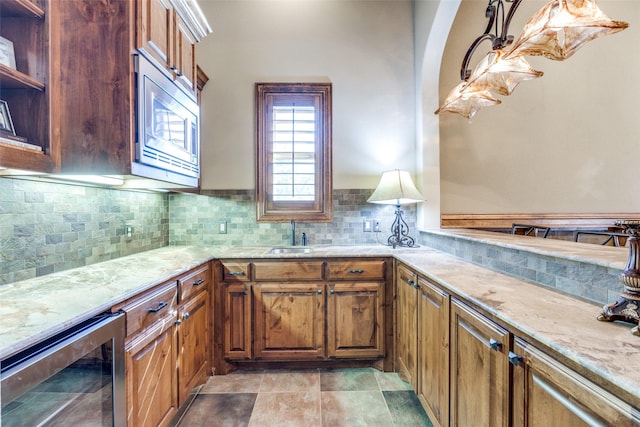 kitchen featuring tasteful backsplash, pendant lighting, stainless steel microwave, and wine cooler