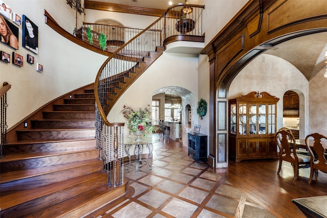 foyer entrance featuring hardwood / wood-style flooring, a towering ceiling, and a chandelier