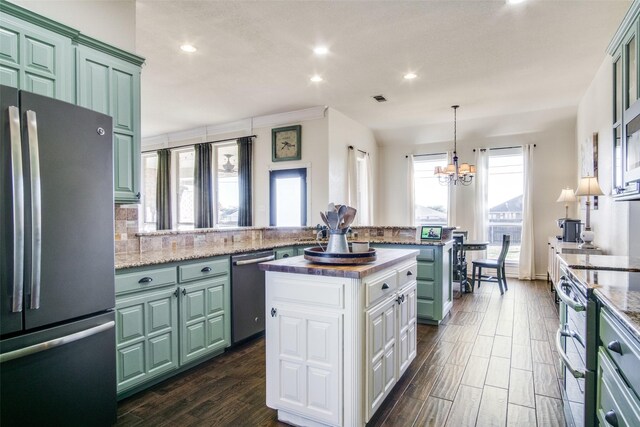 kitchen featuring a kitchen island, tasteful backsplash, a chandelier, white cabinets, and appliances with stainless steel finishes