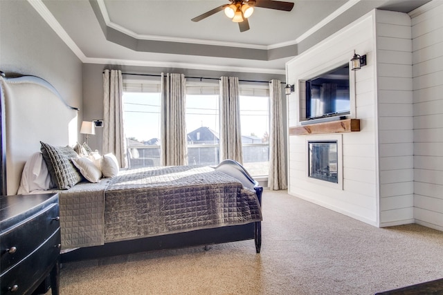 bedroom with carpet flooring, ceiling fan, a tray ceiling, and ornamental molding