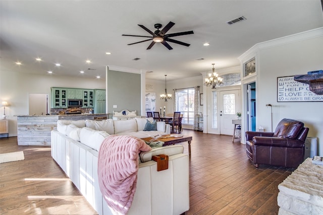 living room featuring dark wood-type flooring, ornamental molding, and ceiling fan with notable chandelier