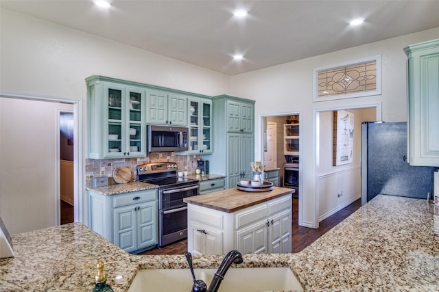 kitchen featuring wood counters, tasteful backsplash, sink, white cabinets, and stainless steel appliances