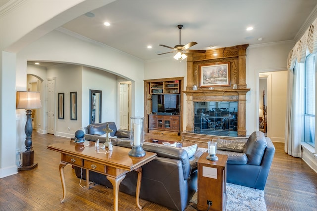 living room featuring wood-type flooring, ornamental molding, built in features, ceiling fan, and a fireplace