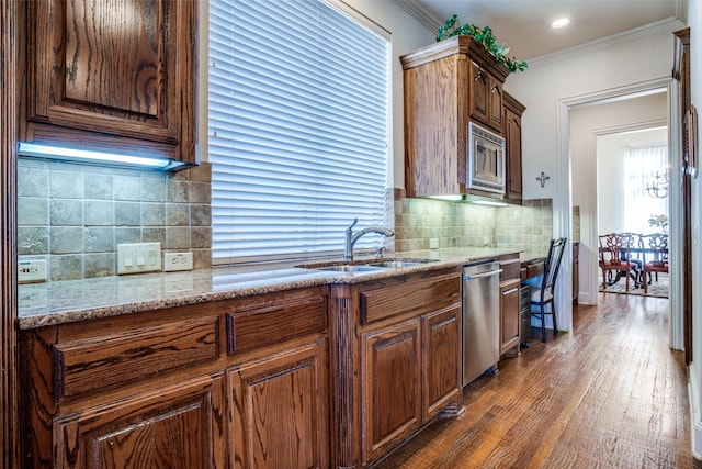 kitchen with dark wood-type flooring, crown molding, tasteful backsplash, appliances with stainless steel finishes, and light stone countertops