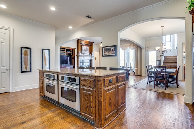 kitchen with pendant lighting, dark hardwood / wood-style floors, a center island, and stainless steel oven