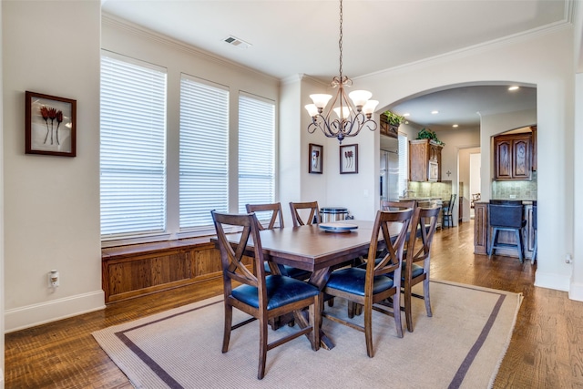 dining room with crown molding, dark hardwood / wood-style flooring, and a chandelier