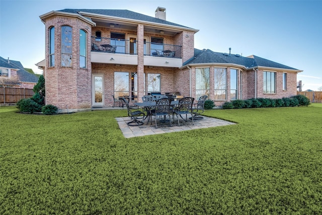 rear view of house featuring a balcony, a patio area, and a lawn