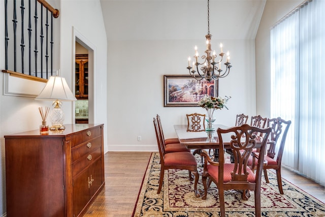 dining space featuring vaulted ceiling, a notable chandelier, and light wood-type flooring