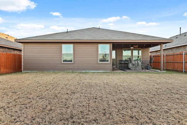 rear view of house with ceiling fan, a patio, and a lawn