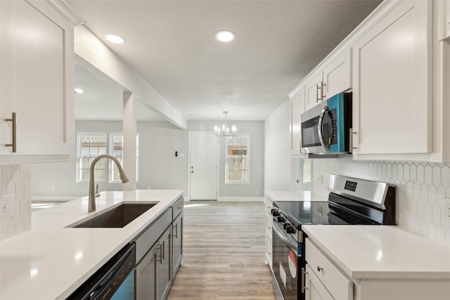 kitchen featuring sink, pendant lighting, stainless steel appliances, decorative backsplash, and white cabinets