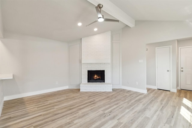 unfurnished living room with a brick fireplace, lofted ceiling with beams, light hardwood / wood-style floors, and ceiling fan