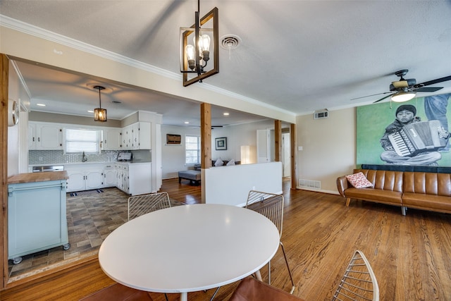 dining area with crown molding, dark wood-type flooring, and ceiling fan