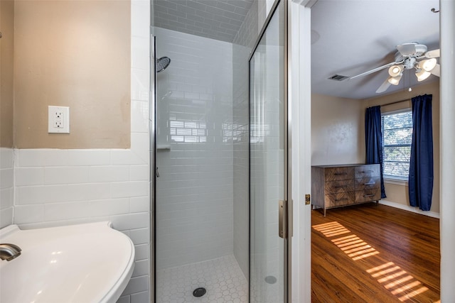 bathroom with sink, tile walls, a shower with door, hardwood / wood-style flooring, and ceiling fan