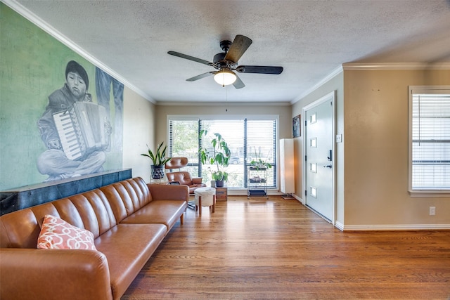 living room featuring wood-type flooring, ceiling fan, a textured ceiling, and crown molding