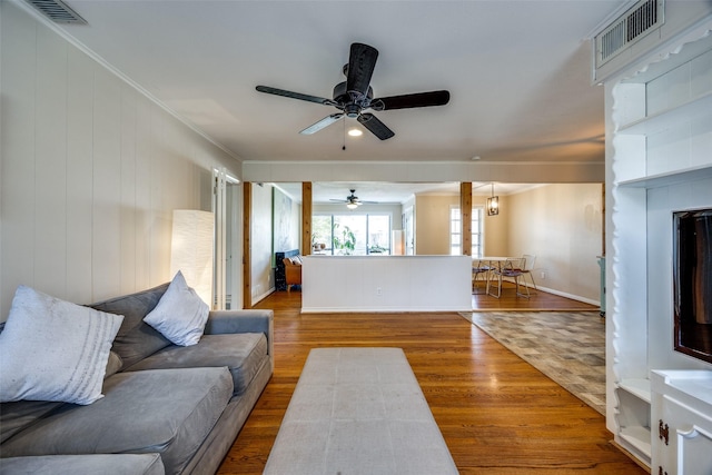 living room featuring hardwood / wood-style flooring, ceiling fan, and crown molding