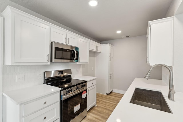 kitchen with sink, light hardwood / wood-style flooring, stainless steel appliances, and white cabinets