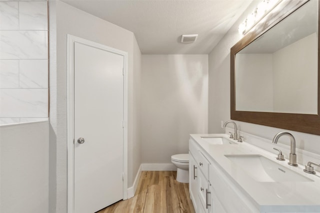 bathroom featuring wood-type flooring, vanity, a textured ceiling, and toilet