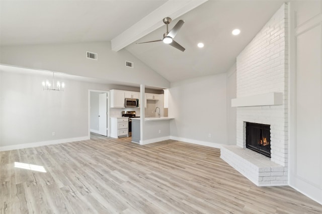 unfurnished living room with ceiling fan with notable chandelier, sink, a brick fireplace, beam ceiling, and light hardwood / wood-style flooring