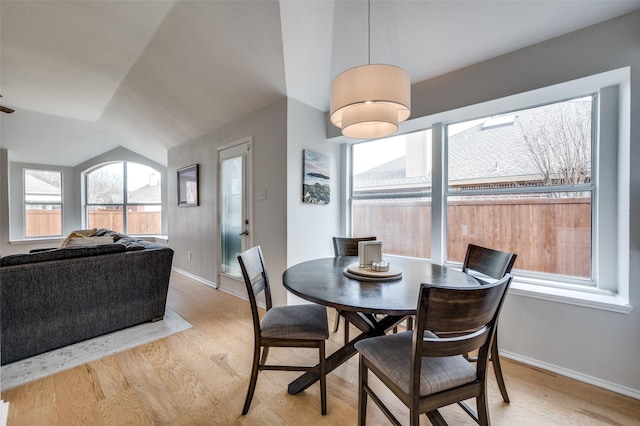 dining room featuring light wood-type flooring and vaulted ceiling